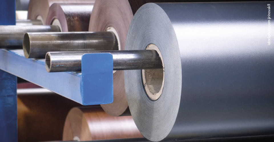 Rouleaux de films vinyle sur des mandrins en acier dans un rayonnage de stockage bleu ; à l'avant, un grand rouleau gris ; derrière, des rouleaux recouverts d'un film imitation bois