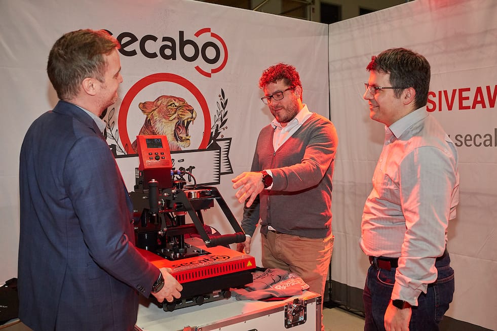 Three managing directors of the Nepata Group present the red Secabo transfer press, the first product manufactured in Wolnzach