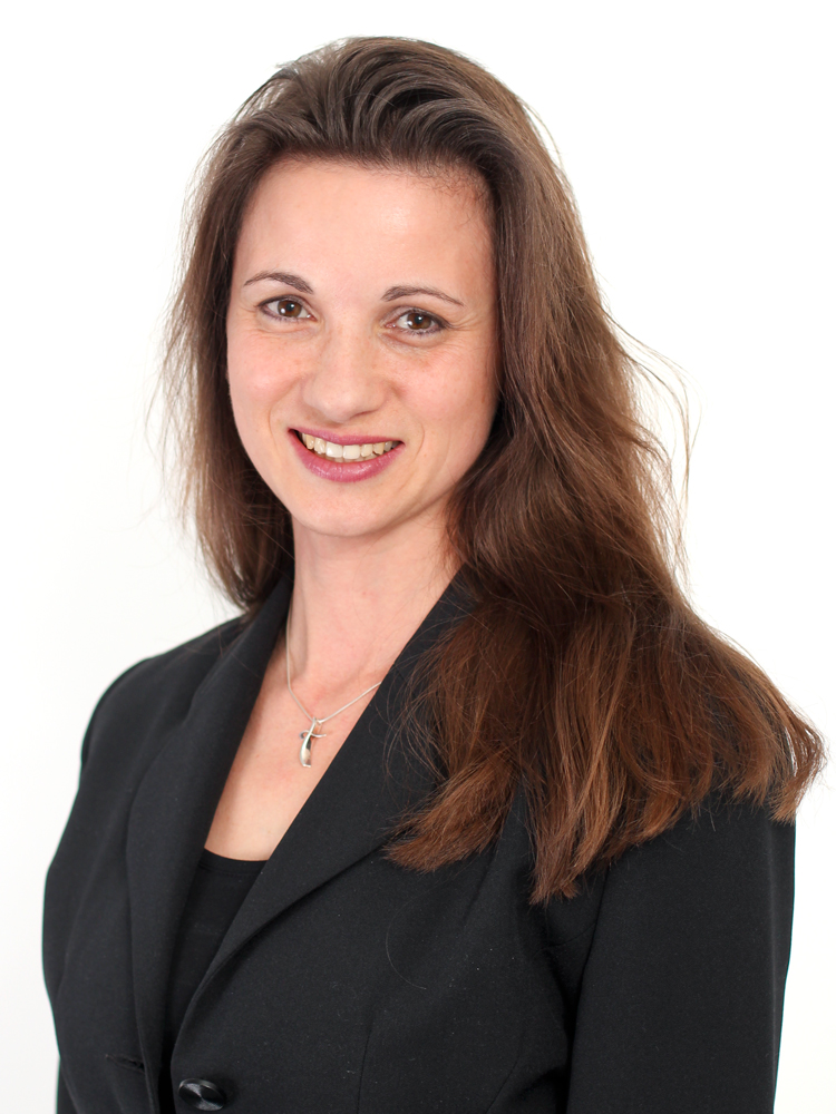 Porträt von Jasmin Alfort, neue Vertriebsmitarbeiterin bei YOW!, mit langen braunen Haaren und schwarzem Blazer, lächelnd vor weißem Hintergrund