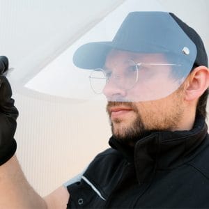 Mann mit Brille und schwarzen Handschuhen trägt ein transparentes Gesichtsvisier an einer dunklen Schirmmütze, Nepata-Visier aus Wolnzach